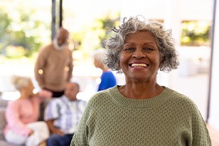 Woman in green sweater smiling with 4 friends blurry in the background