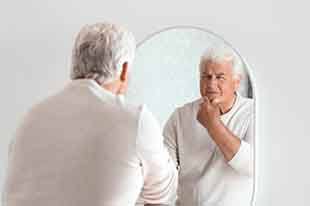 Dentures patient looking in the mirror in Deer Park