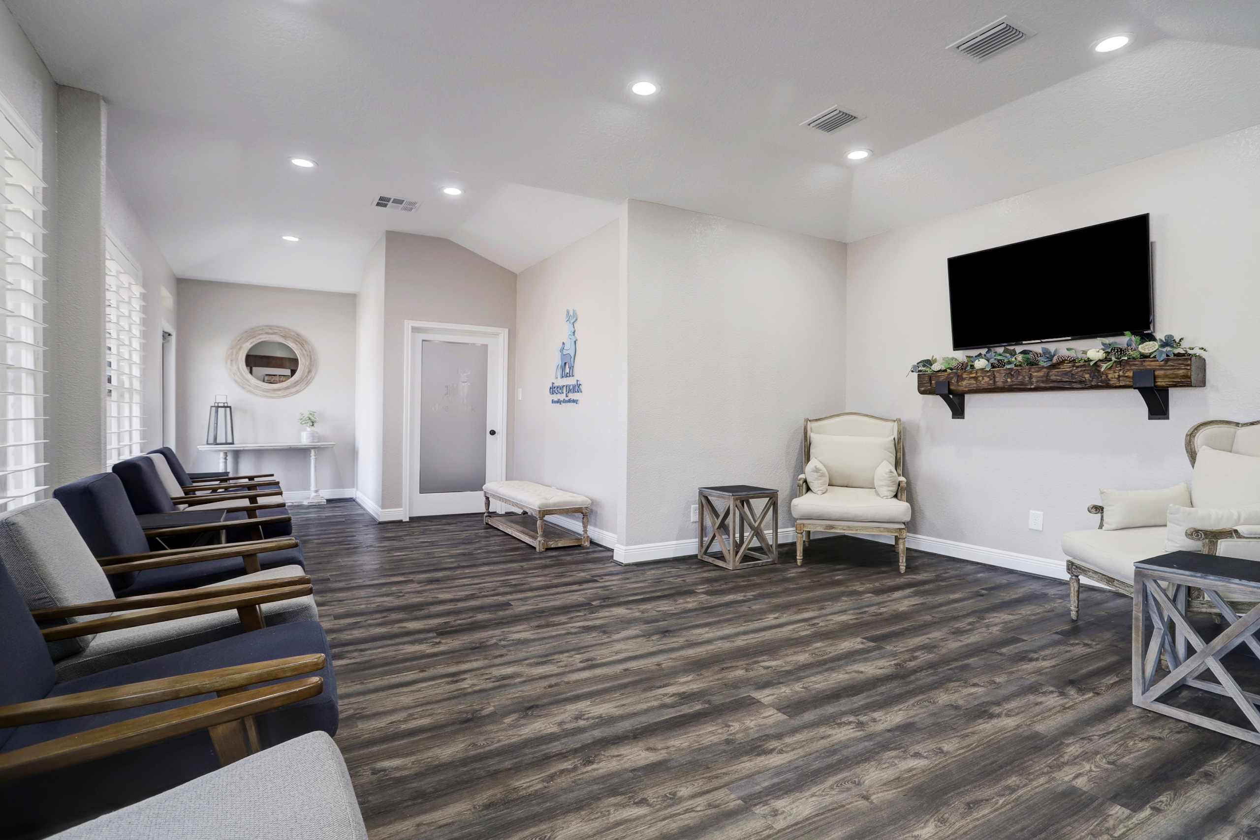 Bright and welcoming waiting area at Deer Park Family Dentistry featuring comfortable chairs, hardwood floors, a mounted TV, and decorative accents creating a relaxing atmosphere – Deer Park Family Dentistry